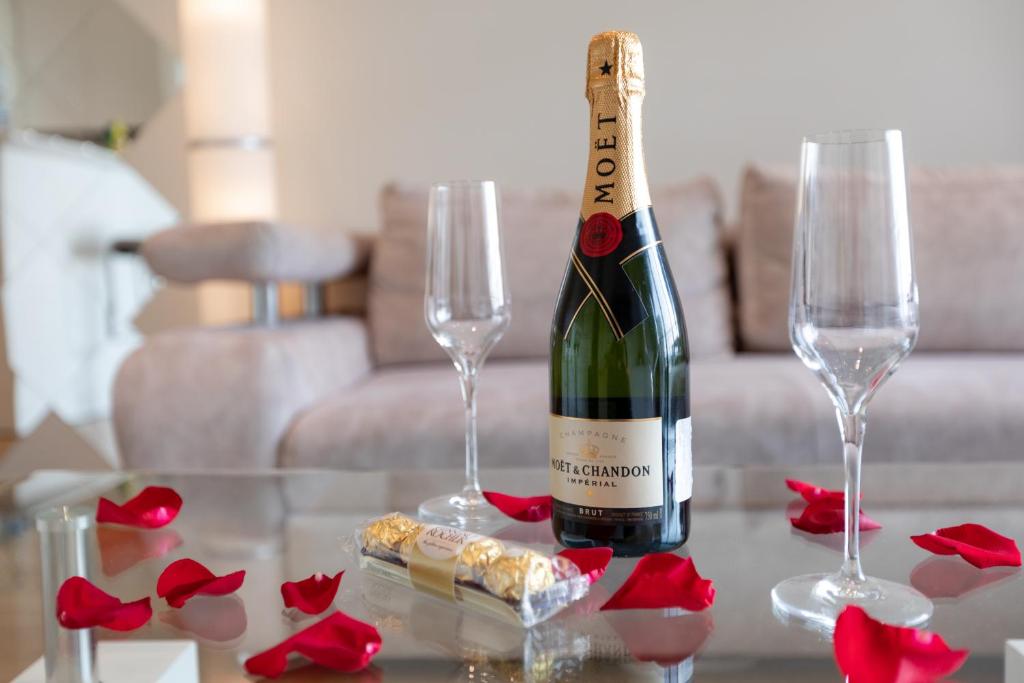 Champagne and two glasses surrounded by red rose petals